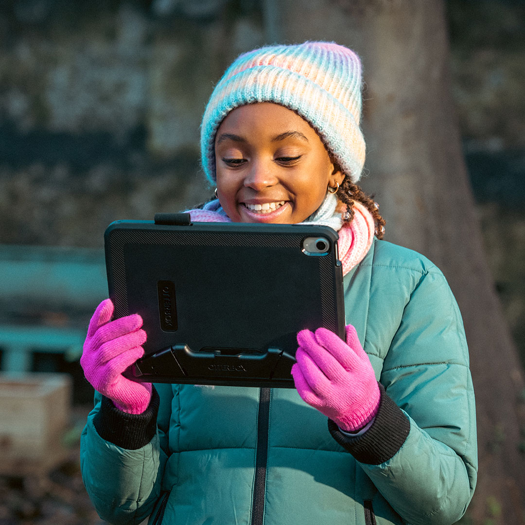 Young girl smiling at a tablet
